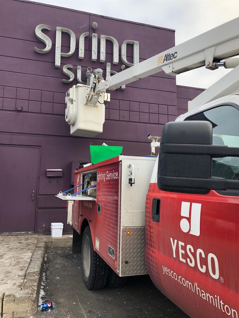 spring sushi sign with white letters on a purple brick building