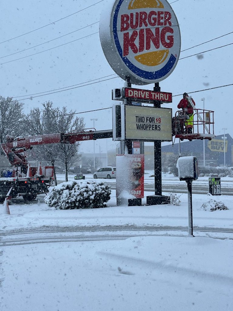 Burger King sign with YESCO bucket ladder servicing the sign with snow blowing